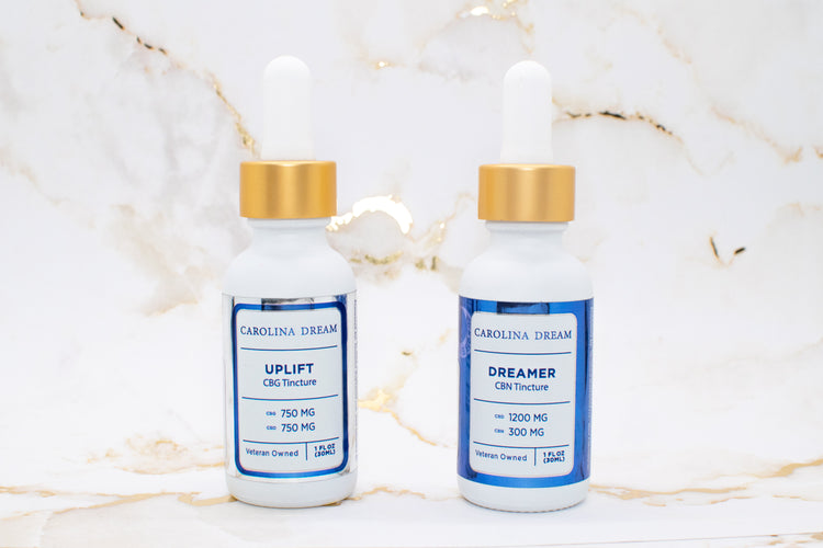 Tinctures from Carolina Dream featuring UPLIFT CBG Tincture and DREAMER CBN Tincture bottles on marble background.